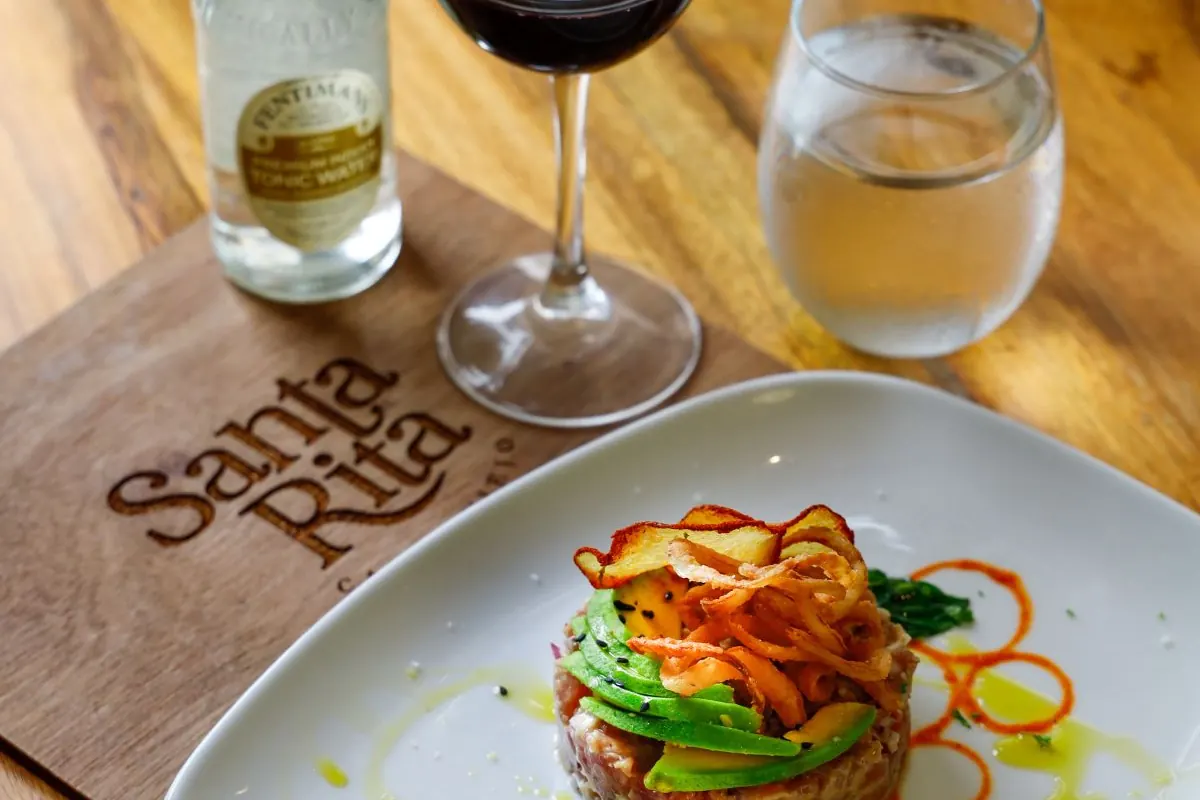 Plato de autor emplatado junto a copas de vino tinto y blanco