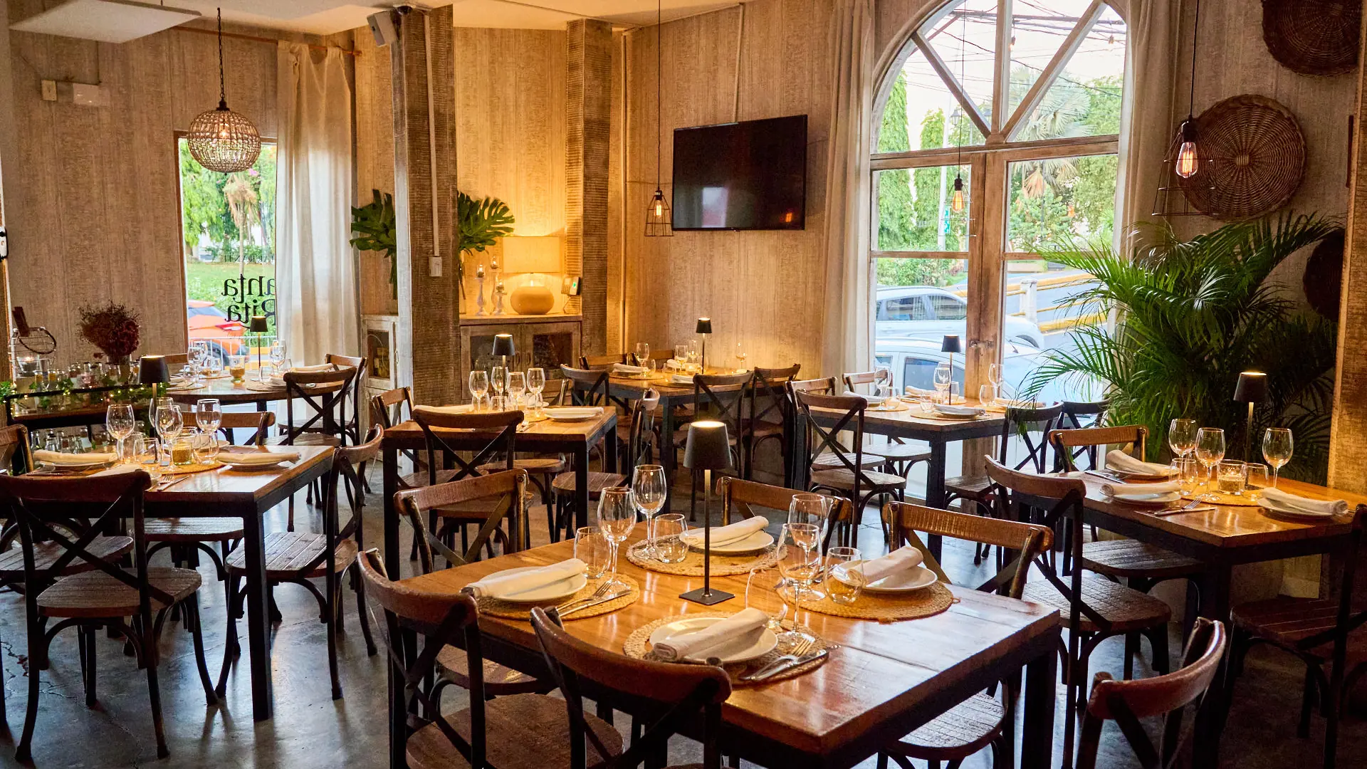 Salón del Restaurante Santa Rita en Casco Viejo con mesas de madera, sillas cross-back y ventanales de arco
