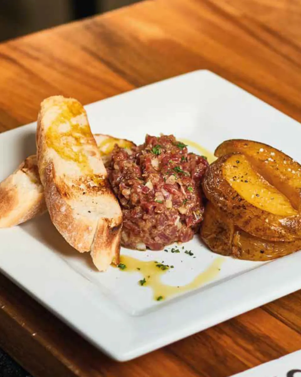 Steak tartar de filete cortado a cuchillo con tostas y patatas